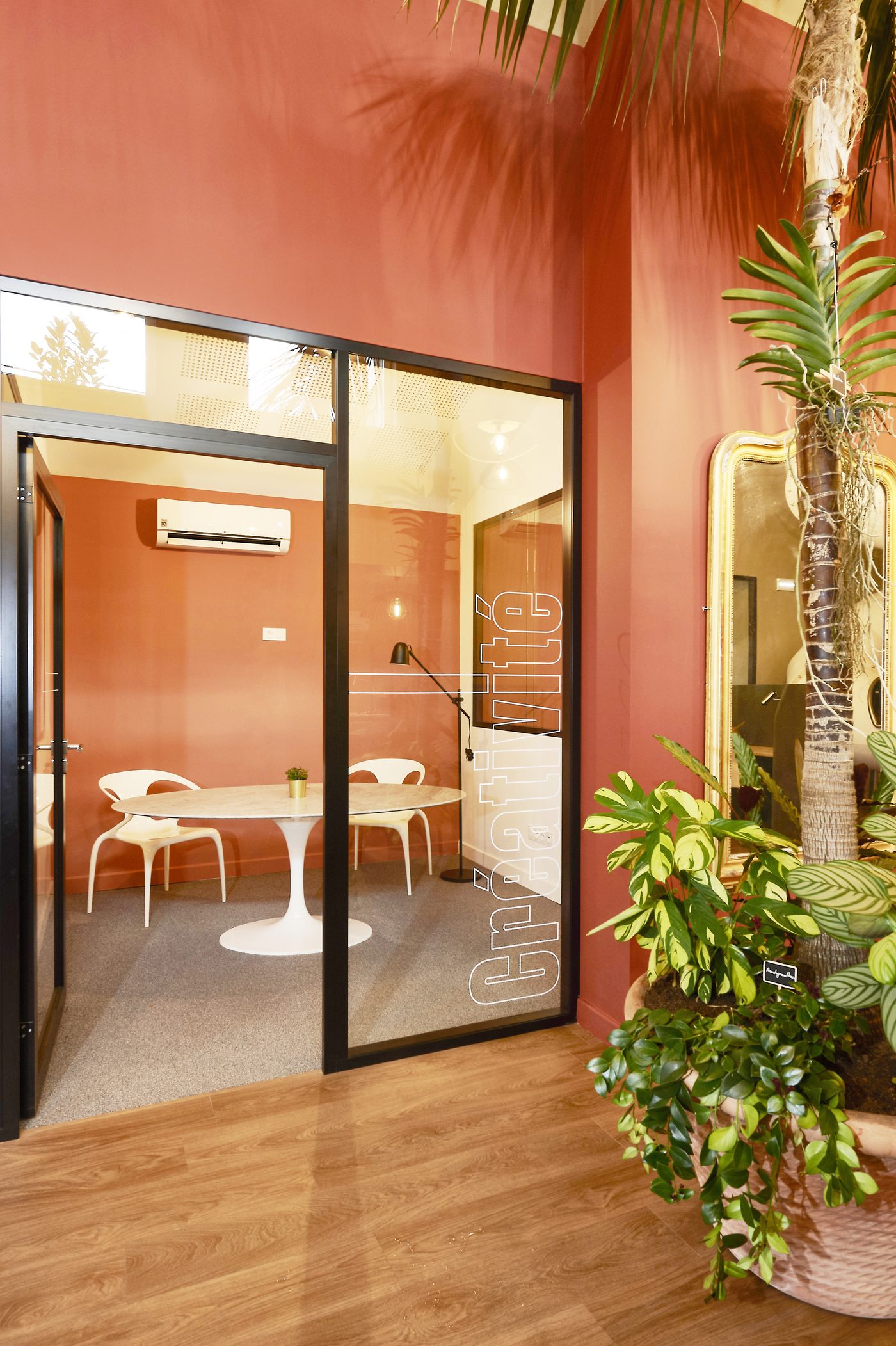 Petite salle de réunion Créativité au Vigean : table ronde en marbre, chaises blanches, mur terracotta
