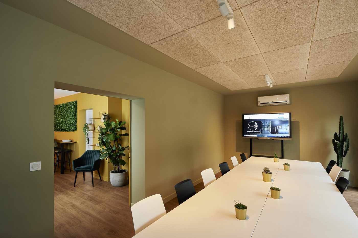 Salle de réunion Synergie au Vigean : grande table, écran interactif, murs vert olive